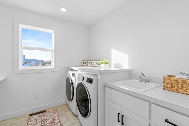 clothes washing area featuring washer and dryer, cabinets, and sink