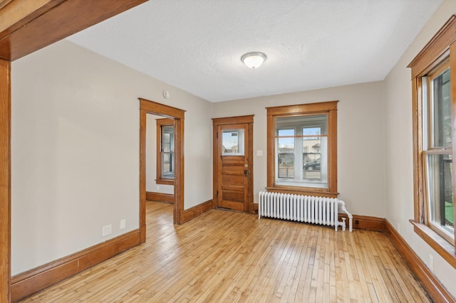 entrance foyer with a healthy amount of sunlight, radiator heating unit, a textured ceiling, and light hardwood / wood-style flooring