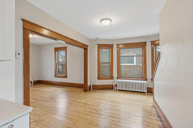 spare room with radiator heating unit and light hardwood / wood-style flooring