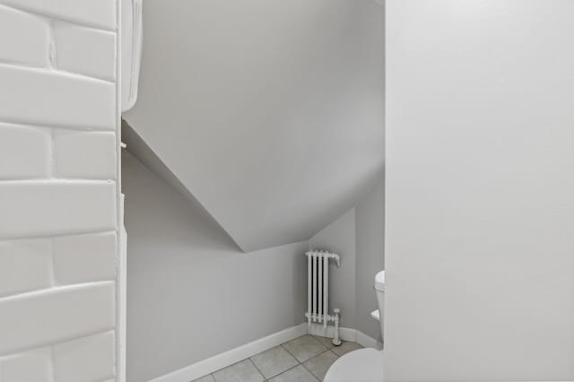 stairway featuring radiator, tile patterned flooring, and vaulted ceiling