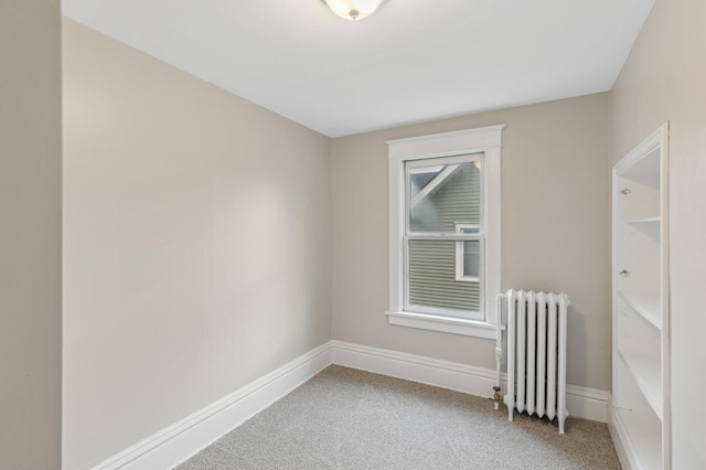 spare room with radiator heating unit and carpet floors