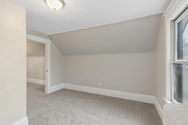 bonus room featuring radiator heating unit, light colored carpet, and lofted ceiling