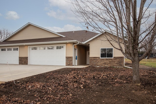 ranch-style home with stone siding, a shingled roof, an attached garage, and driveway