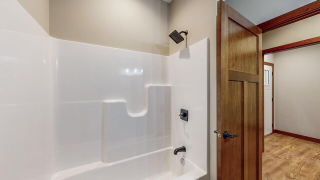 bathroom featuring shower / bathing tub combination, baseboards, and wood finished floors