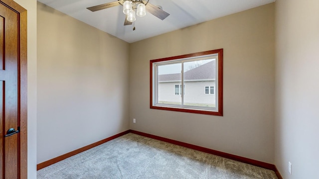 carpeted empty room with ceiling fan and baseboards