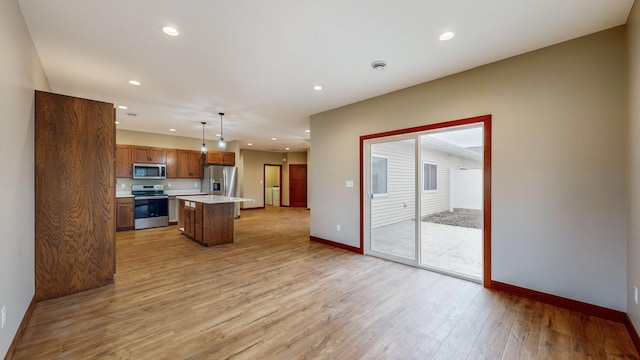 kitchen with stainless steel appliances, recessed lighting, light countertops, a kitchen island, and light wood-type flooring