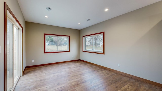 empty room with light wood-style flooring, visible vents, baseboards, and recessed lighting