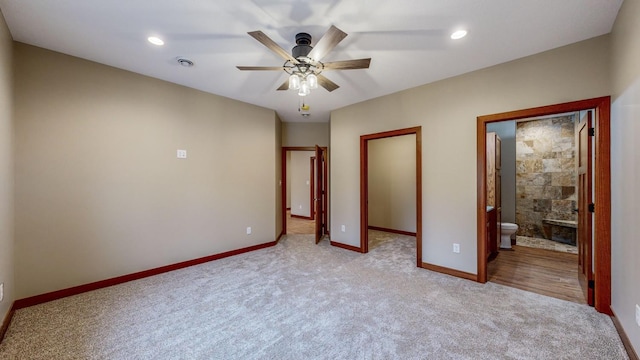 unfurnished bedroom featuring a walk in closet, recessed lighting, light colored carpet, ensuite bathroom, and baseboards