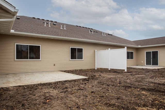 rear view of house featuring a shingled roof and a patio area