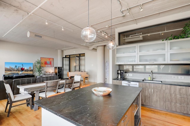 kitchen with sink, decorative light fixtures, light hardwood / wood-style floors, and a kitchen island