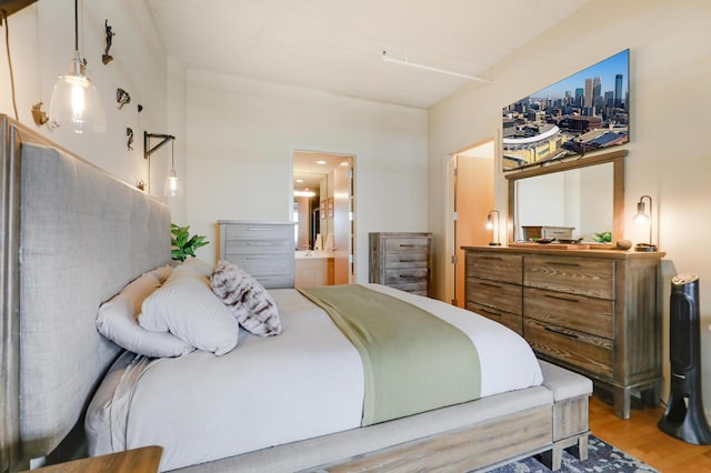 bedroom featuring connected bathroom and hardwood / wood-style flooring