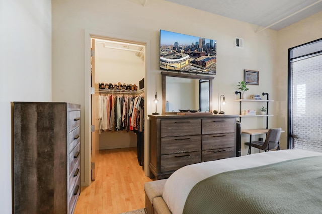 bedroom with a spacious closet, light hardwood / wood-style floors, and a closet