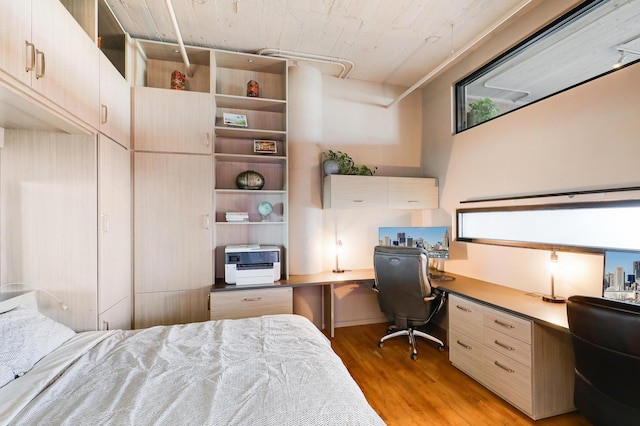 bedroom with built in desk and light hardwood / wood-style floors