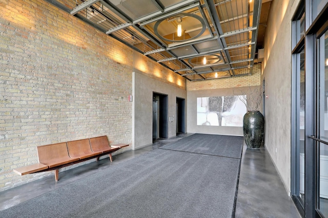 miscellaneous room featuring brick wall, elevator, and a high ceiling