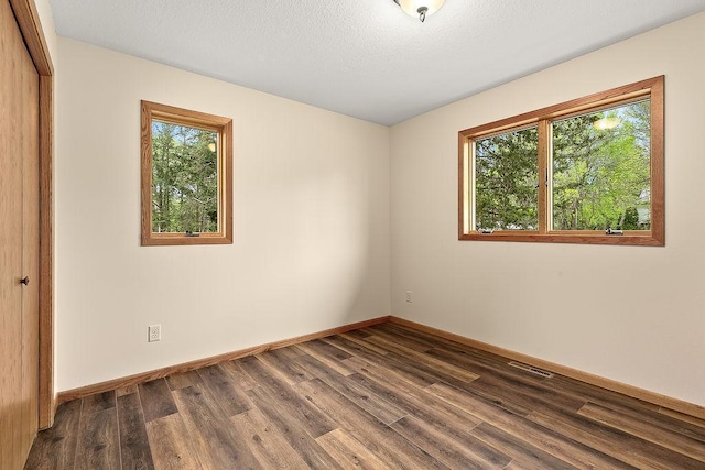 unfurnished room with a textured ceiling and dark wood-type flooring