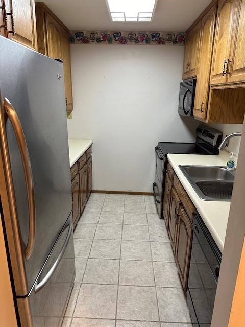 kitchen with light tile patterned floors, sink, and black appliances