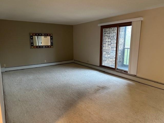 carpeted empty room featuring a baseboard radiator