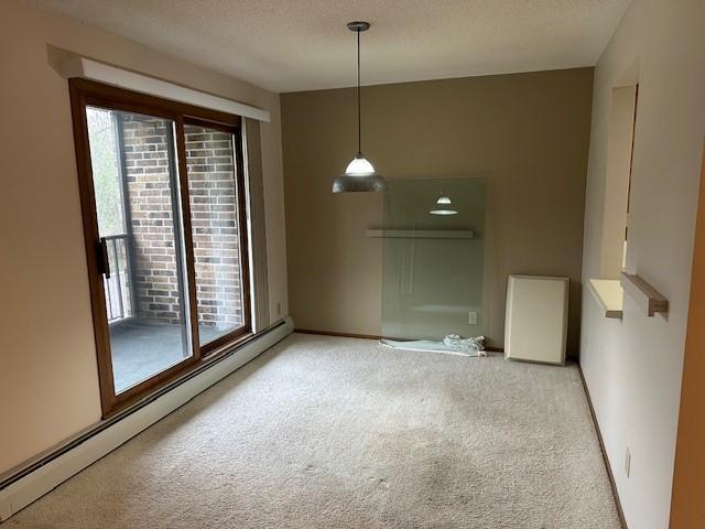 spare room with carpet flooring, a textured ceiling, and a baseboard radiator