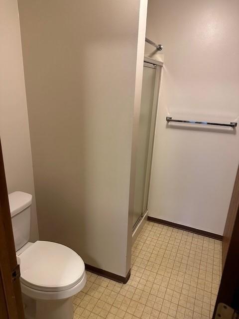 bathroom featuring toilet and a shower with shower door