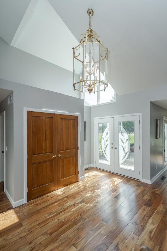 entrance foyer with high vaulted ceiling, french doors, baseboards, and wood finished floors