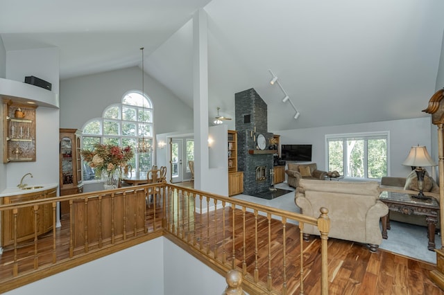 kitchen featuring a fireplace, open floor plan, a sink, wood finished floors, and high vaulted ceiling