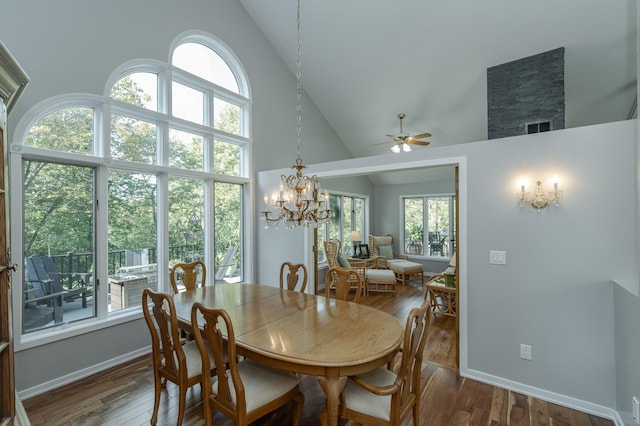 dining room with ceiling fan with notable chandelier, high vaulted ceiling, wood finished floors, and baseboards