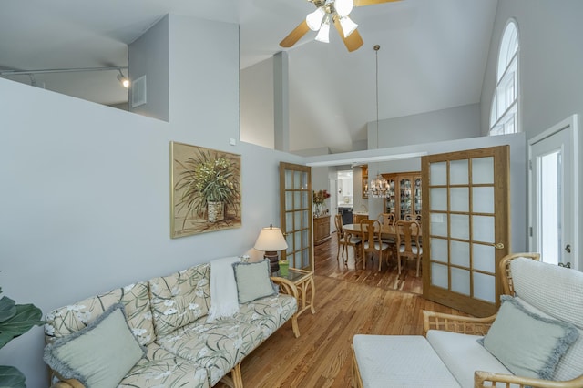 living area with light wood-style floors, ceiling fan, high vaulted ceiling, and french doors