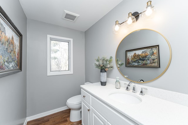 bathroom with toilet, wood finished floors, vanity, visible vents, and baseboards