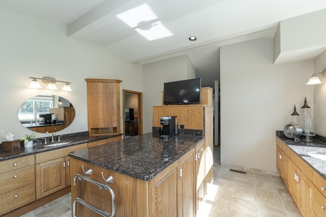 kitchen with lofted ceiling, a sink, a center island, dark stone counters, and stone finish floor