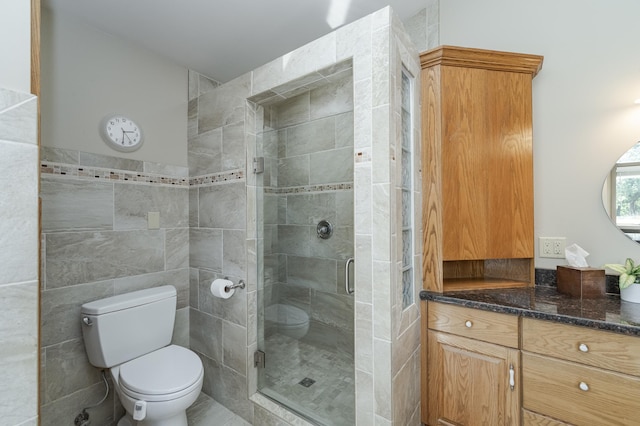 full bathroom with toilet, a shower stall, tile walls, and vanity