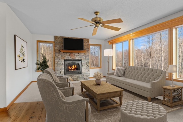 living room with hardwood / wood-style floors, a stone fireplace, plenty of natural light, and ceiling fan