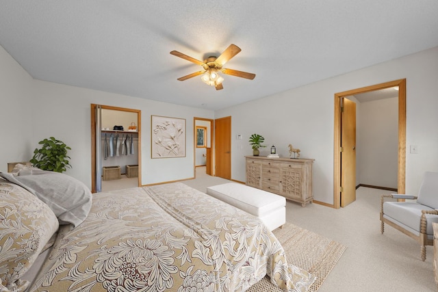 bedroom with a spacious closet, ceiling fan, light colored carpet, a textured ceiling, and a closet