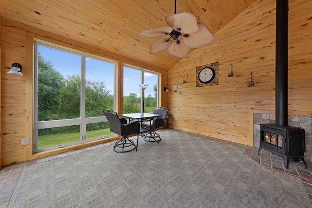 unfurnished sunroom with a wood stove, vaulted ceiling, a healthy amount of sunlight, and wood ceiling