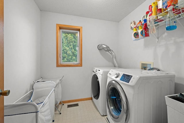 clothes washing area with a textured ceiling, separate washer and dryer, and sink