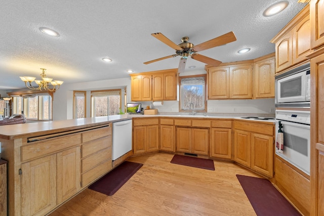 kitchen with kitchen peninsula, a textured ceiling, white appliances, sink, and light hardwood / wood-style floors