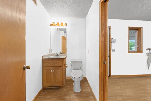 bathroom featuring vanity, wood-type flooring, a textured ceiling, and toilet