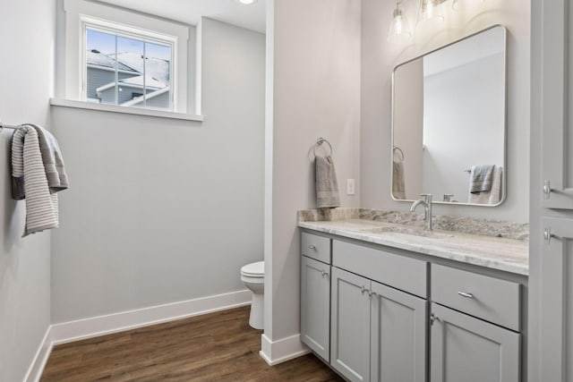 bathroom with toilet, wood-type flooring, and vanity