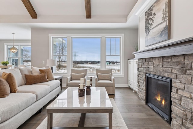 living room with dark wood-type flooring, beamed ceiling, and a stone fireplace