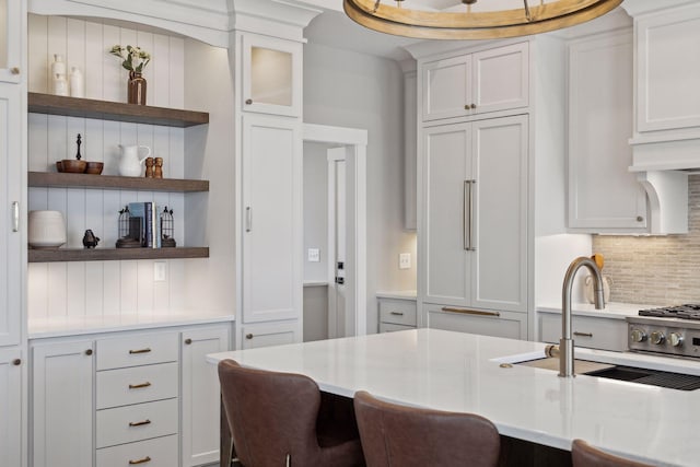 kitchen featuring paneled refrigerator, backsplash, white cabinets, and sink