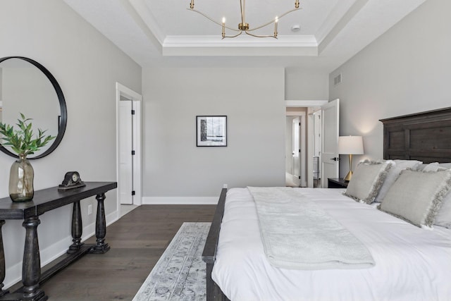 bedroom featuring a tray ceiling, dark hardwood / wood-style flooring, crown molding, and a notable chandelier