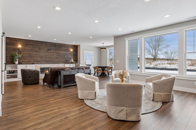 living room with a fireplace, wood-type flooring, and wooden walls