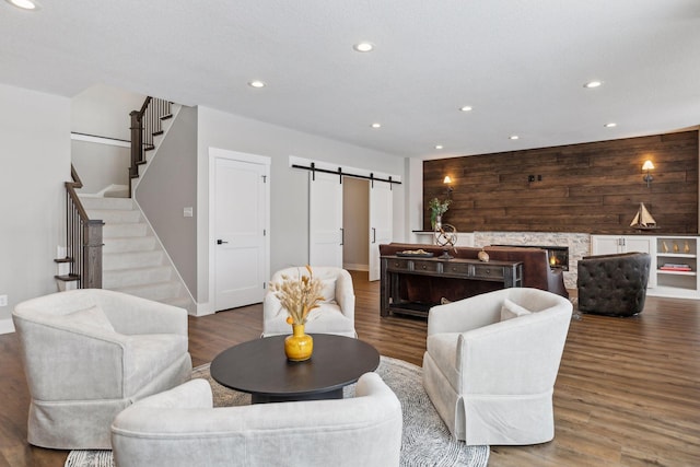 living room featuring a barn door, wood-type flooring, a fireplace, and wood walls