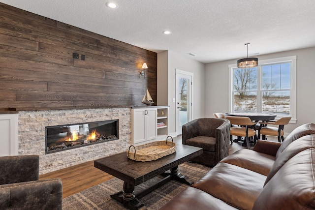 living room with a fireplace, wood walls, a textured ceiling, and hardwood / wood-style floors