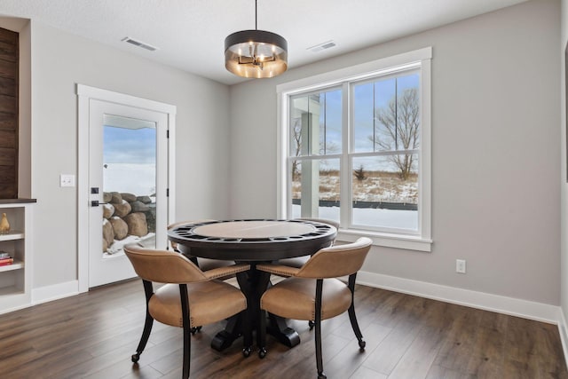 dining room featuring a textured ceiling, dark hardwood / wood-style flooring, and an inviting chandelier