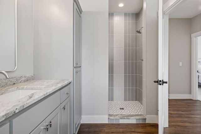 bathroom with vanity, tiled shower, and hardwood / wood-style floors