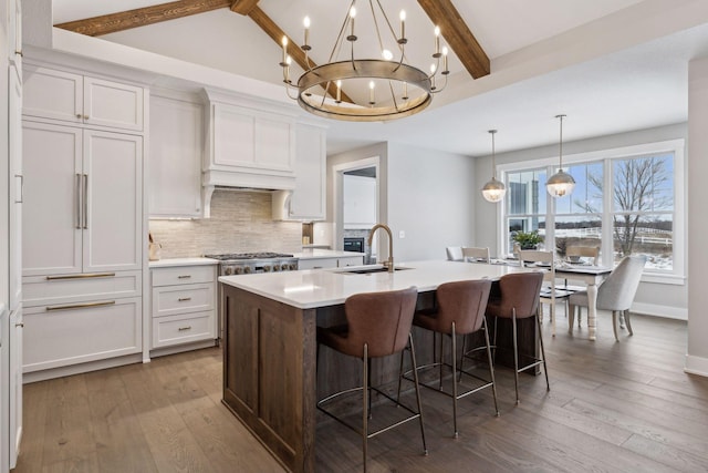 14320 47th St N, Stillwater, MN 55082 - kitchen with a center island with sink, tasteful backsplash, light countertops, beamed ceiling, and white cabinetry
