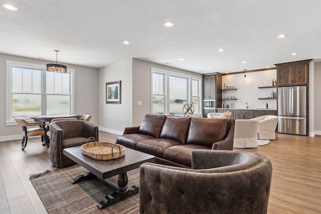 14320 47th St N, Stillwater, MN 55082 - living room featuring light wood-style flooring, a textured ceiling, recessed lighting, and bar