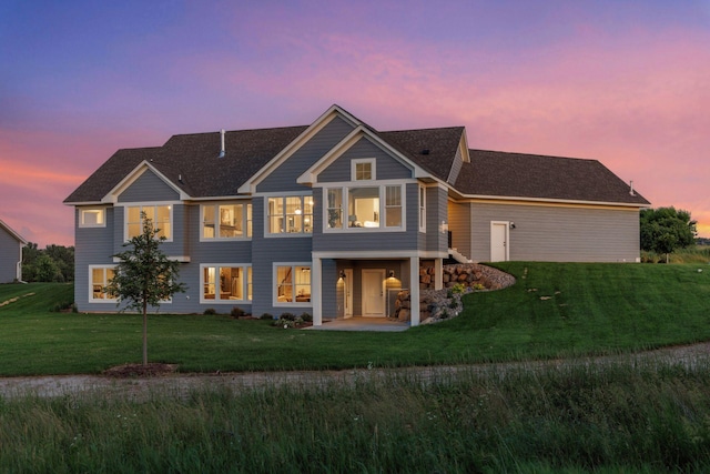 14320 47th St N, Stillwater, MN 55082 - back of property at dusk with a lawn, a patio area, and roof with shingles