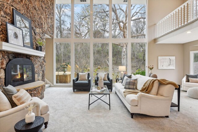 carpeted living room featuring a towering ceiling and a fireplace