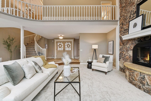 living room with a towering ceiling, carpet floors, and a stone fireplace